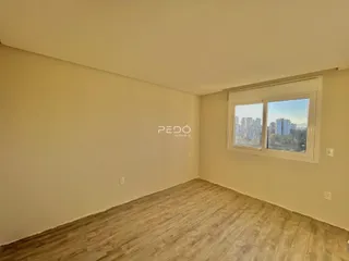 Ambiente interno de uma sala com piso de madeira e vista da cidade.