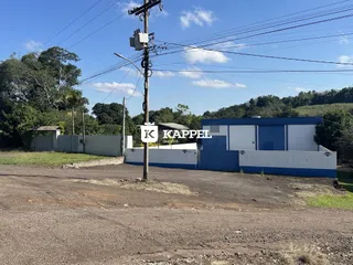 Vista externa da propriedade mostrando um muro e estruturas azuis sob um céu claro.