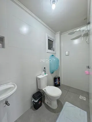 Foto de um banheiro com revestimento branco e piso claro.