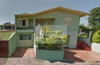 Fachada de uma casa em Lajeado, Brasil, com paredes verdes e piso de tijolo aparente.