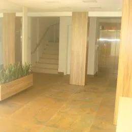 Corredor interno com piso de madeira clara.