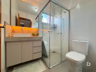 Foto de um banheiro com box de vidro e louças brancas.