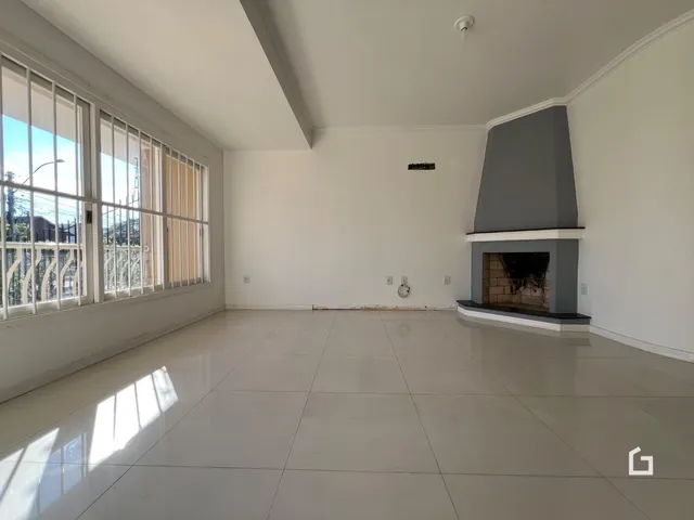 Sala de estar ampla com grandes janelas e lareira.