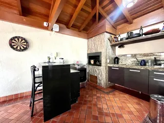 Cozinha com piso de tijolo vermelho e forro de madeira aparente.
