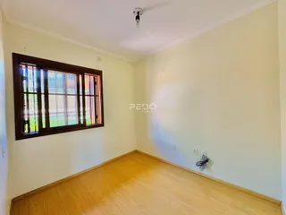 Sala de estar com piso de madeira e janela de madeira.