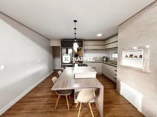 Foto de uma cozinha moderna com mesa de jantar de madeira e armários brancos.