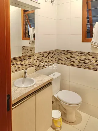 Foto interna de um banheiro com revestimento de azulejos e louças sanitárias.