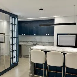 Vista de uma cozinha moderna com bancada e banquetas em um imóvel.