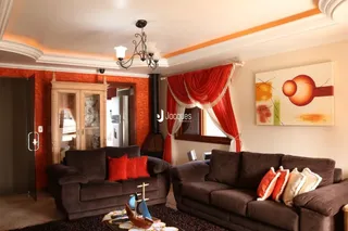 Sala de estar com sofá e portas de madeira em um imóvel no Brasil.