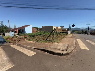 Vista externa de uma rua com casas no fundo sob céu claro.