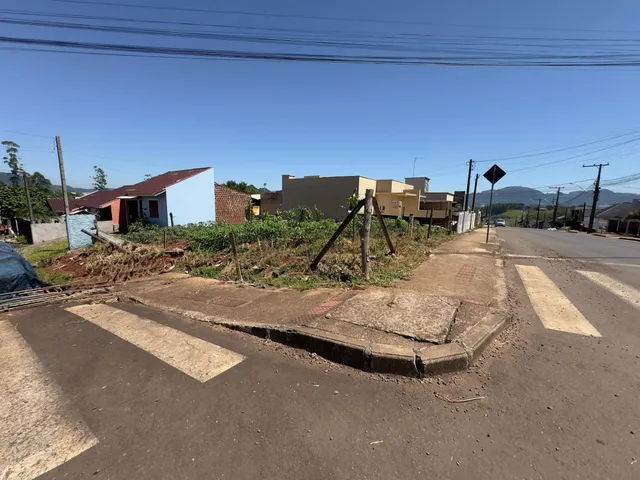 Vista externa de uma rua com casas no fundo sob céu claro.