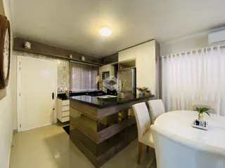 Ambiente de sala de estar e cozinha com ilha em imóvel no Brasil.