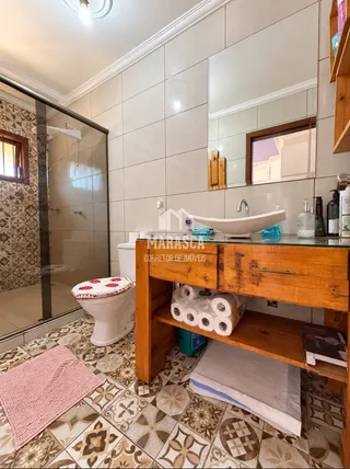 Foto de um banheiro com revestimento cerâmico e móveis de madeira.