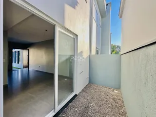 Vista de um corredor interno de uma residência com porta de vidro.