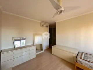 Ambiente interno de uma sala com piso de madeira clara e paredes brancas.