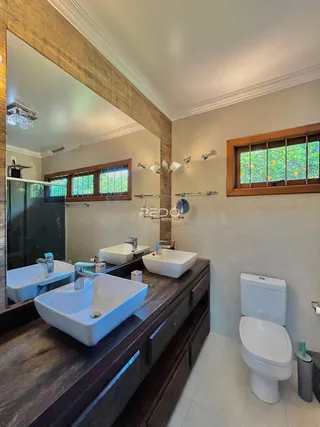 Foto de um banheiro moderno com pias brancas e armários de madeira escura.