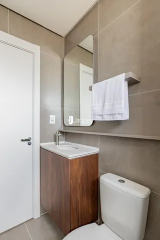 Banheiro moderno com bancada de madeira e azulejos claros.