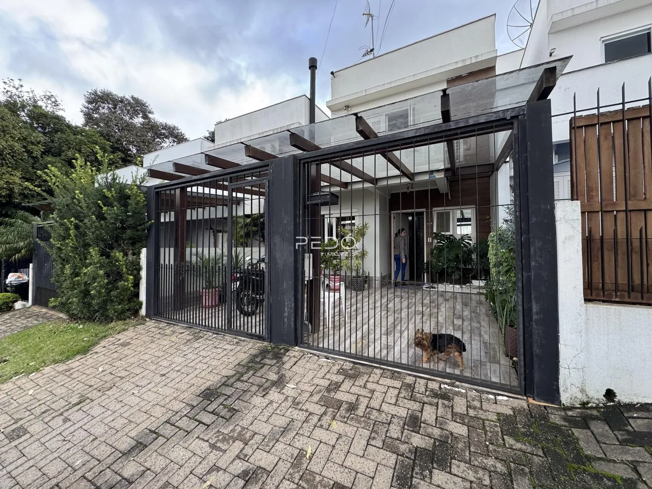 Fachada de uma residência com portão de ferro e calçada de pedras em Lajeado.
