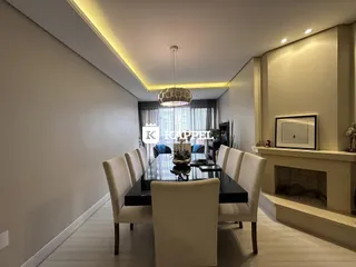 Uma sala de jantar com mesa escura e cadeiras claras em um ambiente moderno.