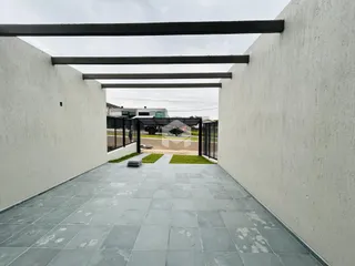 Vista de um pátio interno delimitado por paredes brancas e piso de cerâmica.
