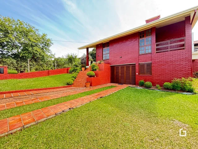 Fachada de casa em tijolo vermelho com jardim e caminho de tijolos.