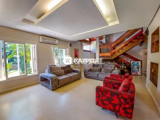 Sala de estar ampla com sofás e iluminação natural vinda de grandes janelas.