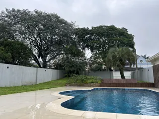 Vista externa de uma piscina e jardim em uma propriedade.