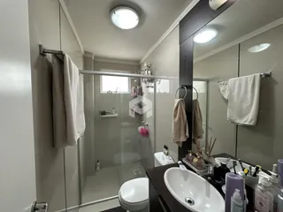 Banheiro com box de vidro e louças brancas em um imóvel.