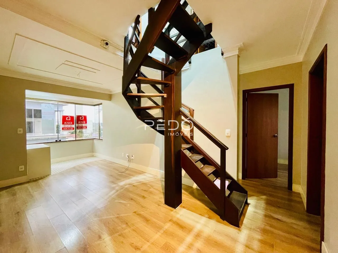 Sala de estar com piso de madeira e escadaria de madeira.