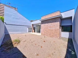 Fachada externa de uma residência com paredes brancas e detalhes em tijolo aparente.