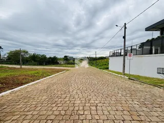 Uma estrada pavimentada se estende ao longo de uma propriedade com cerca branca.