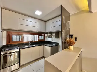Foto de uma cozinha moderna com armários brancos e bancadas escuras.