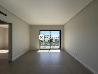 Uma sala ampla com piso claro e porta de vidro voltada para o exterior.