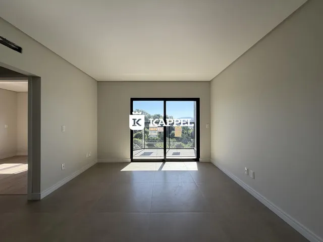 Uma sala ampla com piso claro e porta de vidro voltada para o exterior.