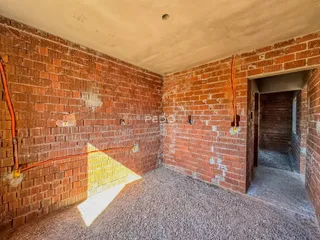 Parede de tijolos aparentes com piso de cascalho em um ambiente interno.