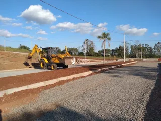 Uma estrada de terra com uma máquina amarela está na paisagem.