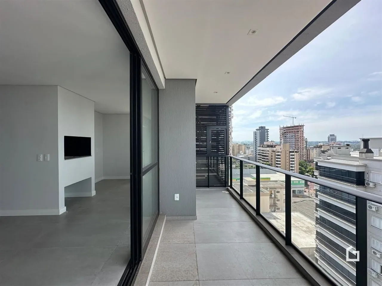Interior de um apartamento com vista para a cidade através de uma varanda.