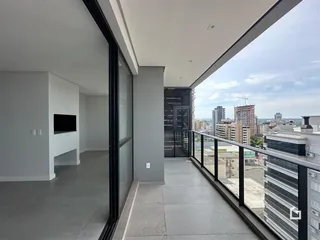 Interior de um apartamento com vista para a cidade através de uma varanda.