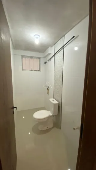 Hall de corredor com um vaso sanitário branco em um imóvel.