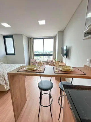 Vista de uma sala de jantar com piso de madeira clara e grande janela.