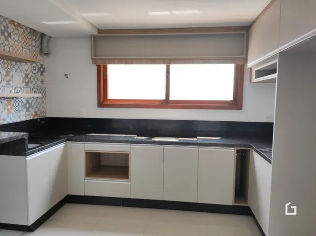Cozinha com armários brancos e bancadas escuras.