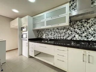 Foto da cozinha com armários brancos e revestimento de azulejos pretos e brancos.