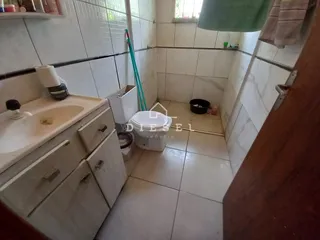 Banheiro com pia e vaso sanitário revestido em azulejos brancos.