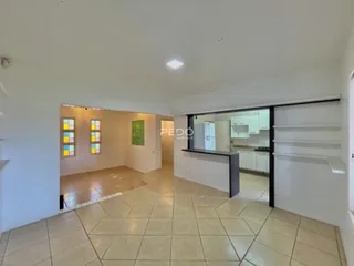 Uma sala de estar com piso de cerâmica clara e paredes brancas.