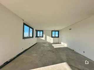 Imagem de um cômodo interno com paredes brancas e piso de concreto.