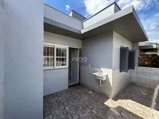 Fachada externa de uma residência com paredes brancas e piso de pedra.