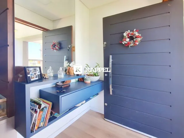 Hall de entrada com prateleira e porta cinza em ambiente residencial.
