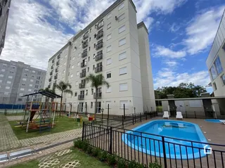 Vista externa de um condomínio residencial com piscina e área de lazer.