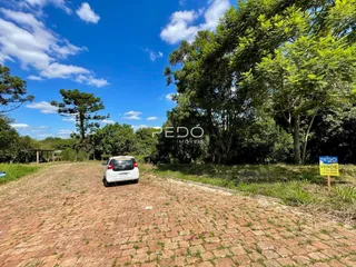 Vista externa de uma propriedade com pátio pavimentado e vegetação ao fundo.