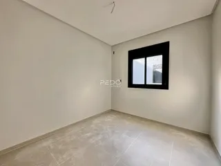 Vista interna de um ambiente vazio com paredes brancas e piso claro.